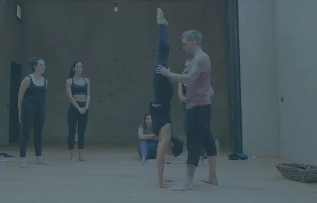 Instructor Kyle Weiger assists a girl student in the gym while others are watching with a teal filter