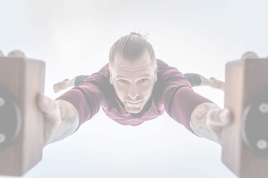 Coach Kyle Weiger doing a handstand on an H-shape Canes Trainer with a camera view underneath white filter applied