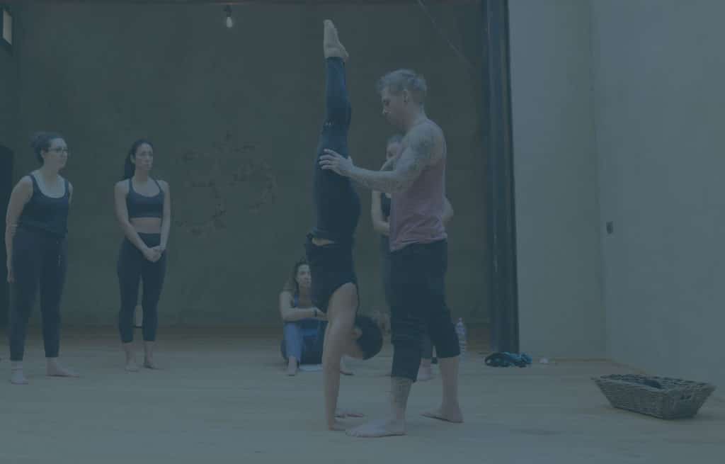 Instructor Kyle Weiger assists a girl student in the gym while others are watching with a teal filter
