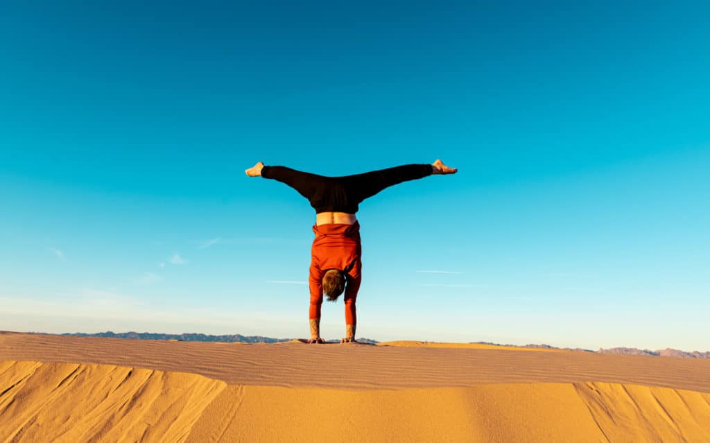 Coach Kyle Weiger doing handstand back facing with outdoor high altitude scenic background while the sun is setting