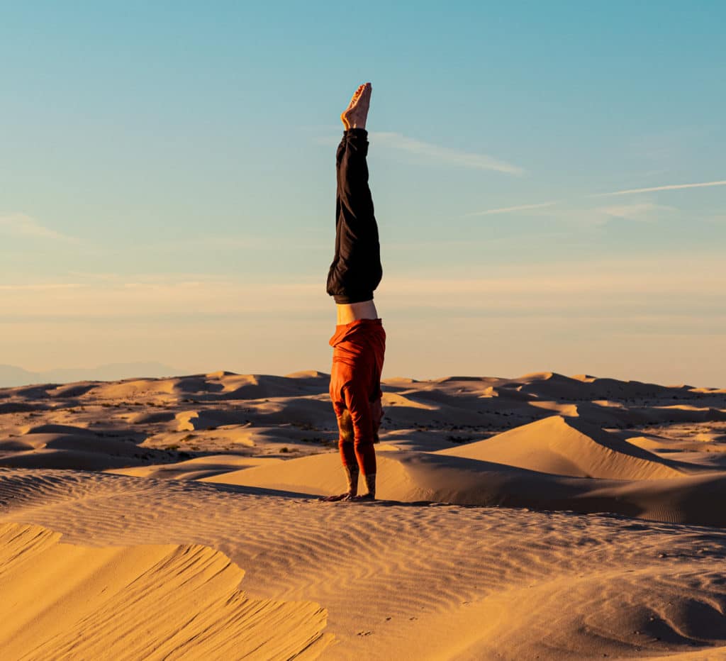 Side view of Coach Kyle Weiger handstanding on a high altitude scenic background while the sun is setting