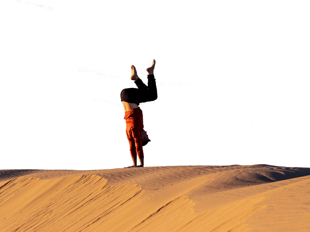 Coach Kyle Weiger doing a tucked handstand on a high altitude dune transparent background