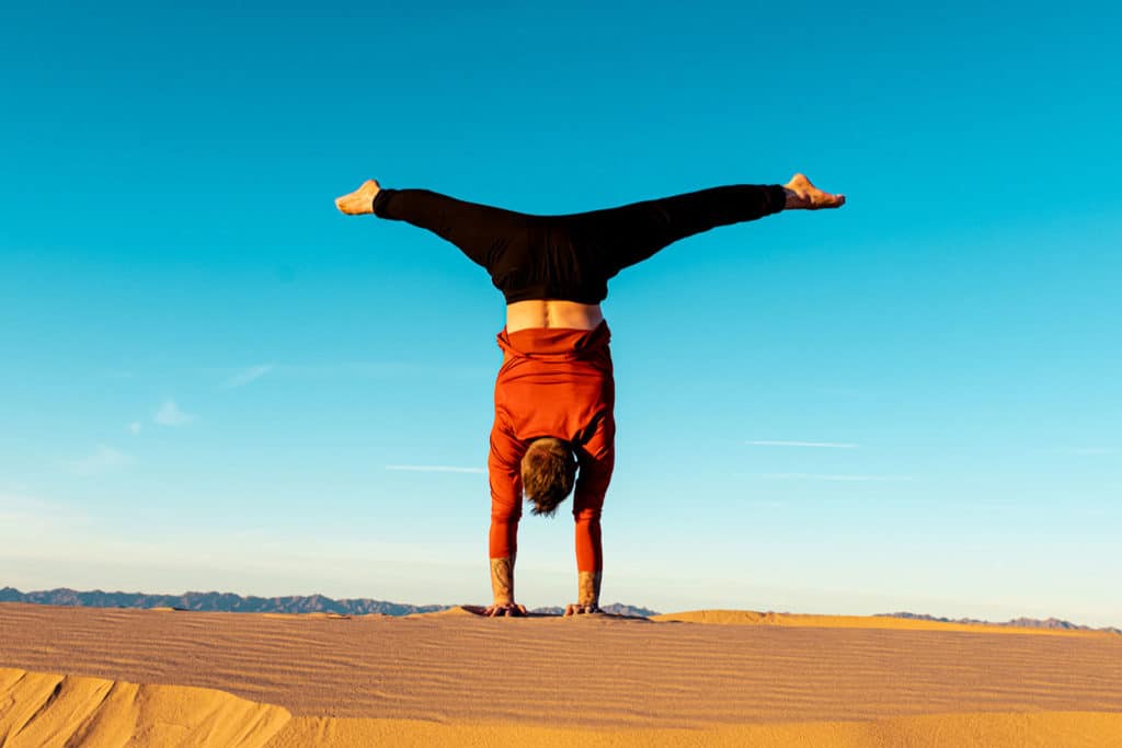 Coach Kyle Weiger doing handstand back facing with outdoor high altitude scenic background while the sun is setting