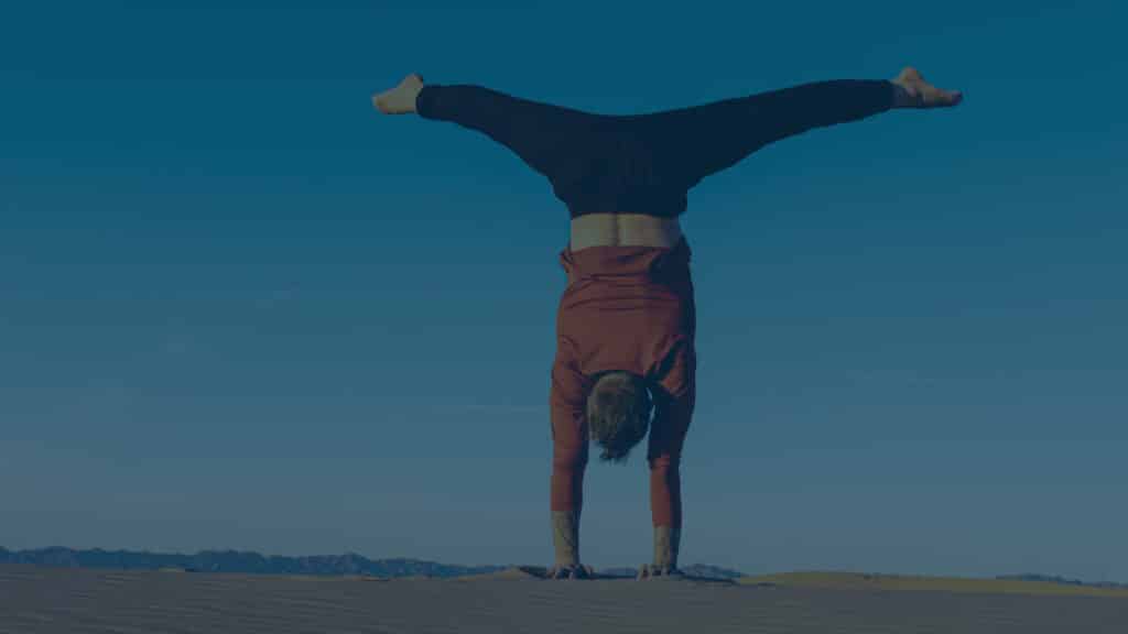 Coach Kyle Weiger doing handstand back facing with outdoor high altitude scenic sunset view and dark teal filter