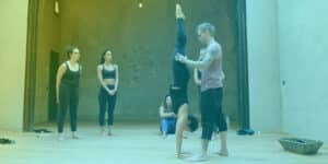 Handstand Coach working with student while other watch.
